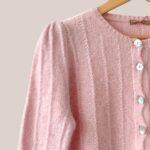 Détail de la maille douce et des finitions du gilet rose poudré pour personne âgée. - forESTIME